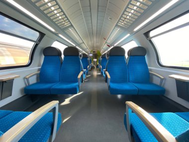 Modern bir yolcu treninin boş kabini. Tren kulübesinde boş mavi koltuklar, koridor manzaralı, insan yok. Modern Avrupa ekonomisi sınıfı hızlı tren iç mimarisi. 