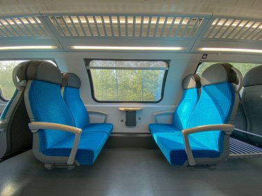 Modern bir yolcu treninin boş kabini. Tren kulübesinde boş mavi koltuklar, koridor manzaralı, insan yok. Modern Avrupa ekonomisi sınıfı hızlı tren iç mimarisi. 