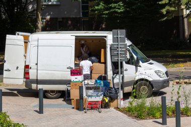 People loading a white van with various boxes and items. clipart