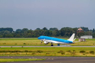 Mavi uçak yeşil bir havaalanına iniyor..