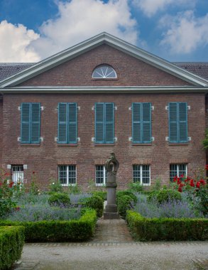 Mavi panjurlu ve yemyeşil bahçeli kırmızı tuğla bina. Yüksek kalite fotoğraf