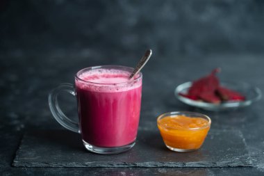 Vanilya ve sütle harmanlanmış taze pancar suyu karışımından pancar vanilyalı latte. Kafedeki masada şeffaf bir bardakta, yakın çekim. Son moda sağlıklı içecek.