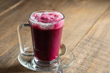 Vanilya ve sütle harmanlanmış taze pancar suyu karışımından pancar vanilyalı latte. Kafedeki masada şeffaf bir bardakta, yakın çekim. Son moda sağlıklı içecek.