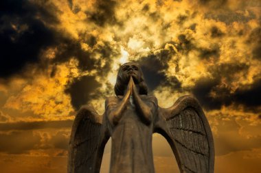 Karanlık gökyüzüne karşı kanatları ve bulutları olan bir meleğin güzel bronz heykeli. Fırtınalı bir arka planı olan güzel melek, yaklaş.