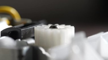 Vitesler mekanik bir cihazda dönüyor. Soyut dönen makine beyaz plastik dişliler. Çarklı tekerlek mekanizması, kapat, makro