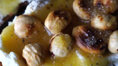 Krem peynirli iki ekmek tostu, kavrulmuş fındık, bal, biber ve tuz tabakta, yakın çekim, üst manzara, döner