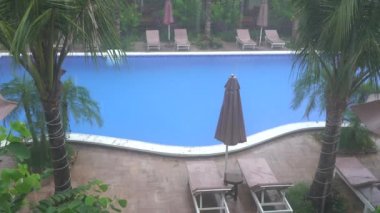 Tropik yaz yağmurları, yüzme havuzuna düşen yağmur damlaları Phu Quoc Adası, Vietnam, Güneydoğu Asya 'daki deniz kıyısında. Doğa ve çevre kavramı