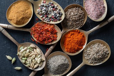 Pirinç kaşıklardaki baharatlar, yakın çekim, üst manzara. Çeşitli biberler, kakule, tuz, kırmızı biber ve safran.