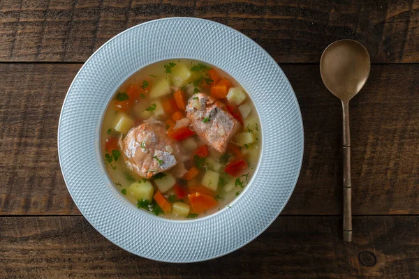 新鮮なサーモンの魚のスープ ニンジン ジャガイモ 赤ピーマンを木製のテーブルの上に白いプレートに入れ 閉じます おいしいディナーは魚のスープとサーモンで構成されています トップ表示 — ストック写真