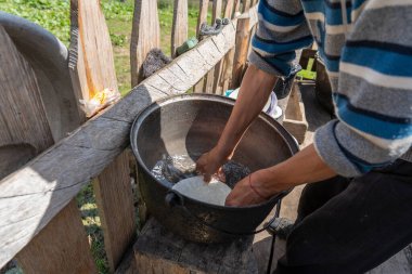 Ukraynalı erkek çiftçi çiftlik bahçesinde bulaşıkları temiz suyla yıkıyor, kapalı, açık havada. Kırsal gelenekler. Batı Ukrayna
