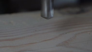 Ahşap delme tahtası. Matkapla ahşap bir levha delilir, makro. İşçi bir makineye delik açıyor. Yakın plan. Yavaş çekim