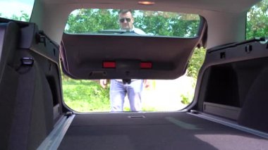 Kafkasyalı adam eski bavulları ve bir çantayı bagaja koyar. Kapat.