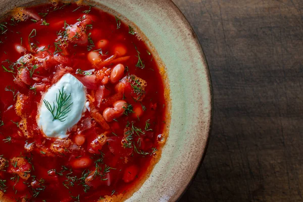 Ukrainian national dish red borsch in a ceramic plate on a wooden background. Beetroot soup is a national dish in Ukraine, close up, top view, copy space for text