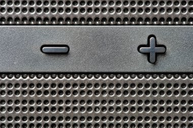 Hoparlör kafesi arka planındaki gri kontrol ve ses düğmeleri. Kablosuz müzik köşesi. Zıt kutuplar kavramı, artı ve eksi. Artı ve eksi düğmeli soyut metalik ağ deseni