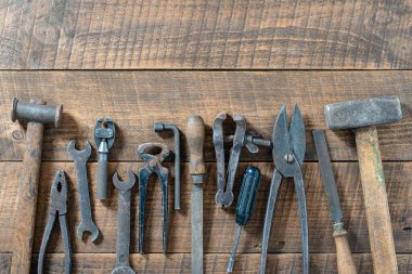 Vintage tools displayed on a background of wooden board, close up, top view, copy space. Dirty set old working tools