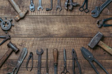 Vintage tools displayed on a background of wooden board, close up, top view, copy space. Dirty set old working tools
