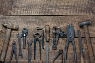 Vintage tools displayed on a background of wooden board, close up, top view, copy space. Dirty set old working tools