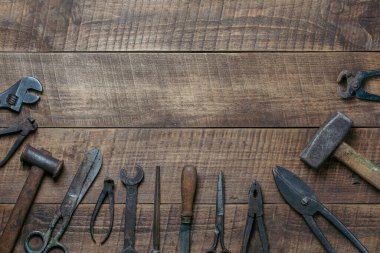 Vintage tools displayed on a background of wooden board, close up, top view, copy space. Dirty set old working tools
