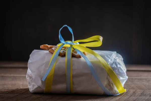 Christmas stollen wrapped in white paper with yellow and blue ribbon for a Christmas gift, traditional German bread for a festive pastry dessert. Close up