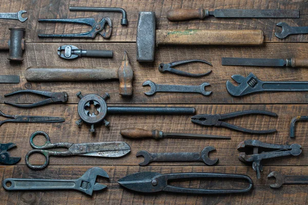 Vintage tools displayed on a background of wooden board, close up, top view. Dirty set old working tools