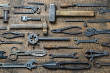 Vintage tools displayed on a background of wooden board, close up, top view. Dirty set old working tools