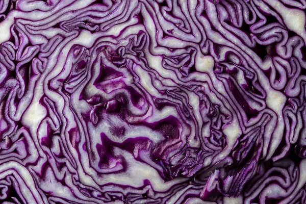 Background of blue cabbage in a section, macro photography. Close up, top view. Texture and pattern of raw purple cabbage