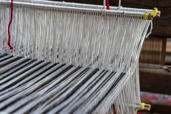 Old hand-weaving vintage wooden loom being used to make fabric, close up, Vietnam