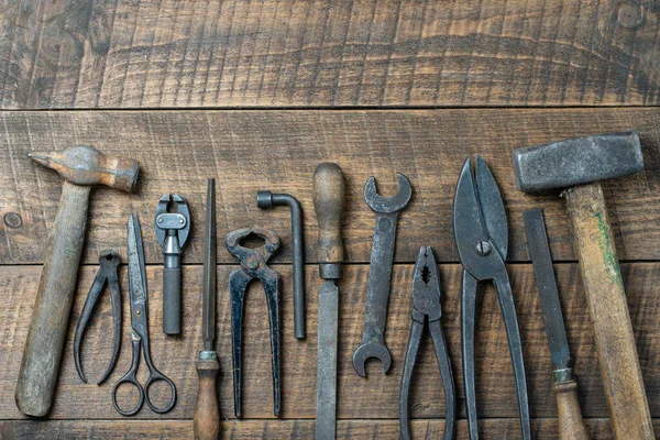 Vintage tools displayed on a background of wooden board, close up, top view, copy space. Dirty set old working tools