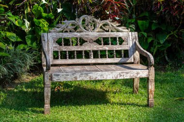 Eğlence alanı ve yeşil çimenlikteki tropik bahçedeki eski ahşap bank. Ubud, Bali Adası, Endonezya, kapatın.