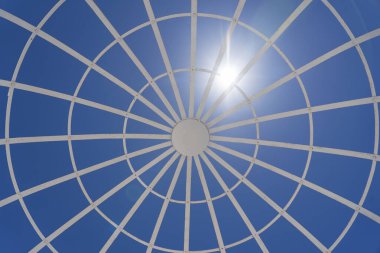 View on metal gazebo above blue sky on sunny summer day, close up