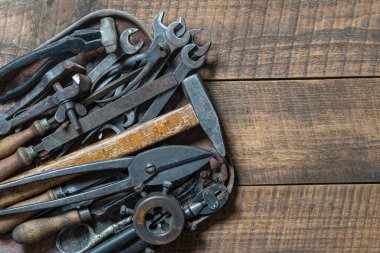 Vintage tools displayed in a old metal tray on a wooden board background, close up, top view, copy space. Dirty set old working tools
