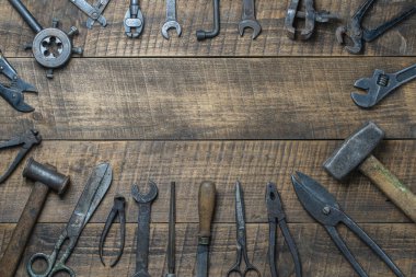Vintage tools displayed on a background of wooden board, close up, top view, copy space. Dirty set old working tools