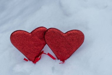 Two red hearts on white snow background for St Valentines day or 14 February, close up