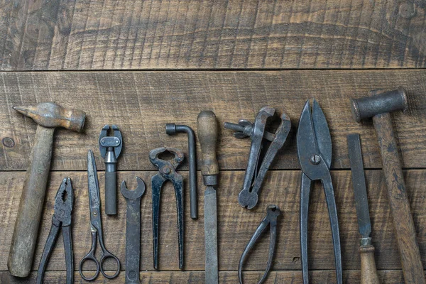 Vintage tools displayed on a background of wooden board, close up, top view, copy space. Dirty set old working tools