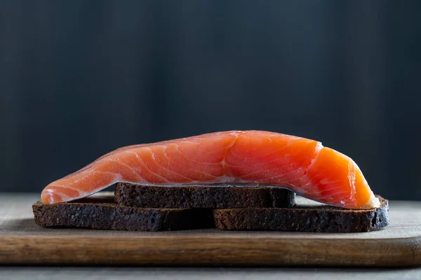 Raw Salmon Fillet Pieces Black Bread Wooden Background Close — Stok fotoğraf