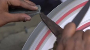 Udaipur, Rajasthan, Hindistan 'da bir pazarda makas keskinleştiren Hintli bir işçiye yakın çekim