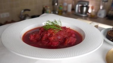 Geleneksel Ukrayna kırmızı çorbası veya kırmızı pancar, patates, havuç, lahana, beyaz kasede fasulye, yakın çekim. Bir tabak kırmızı pancar çorbası çorbası masada döner. Geleneksel Ukrayna yemekleri