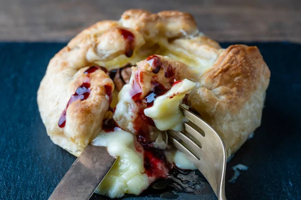 用红莓果酱 叉子和刀叉在松饼上烤的卡门贝尔奶酪 — 图库照片