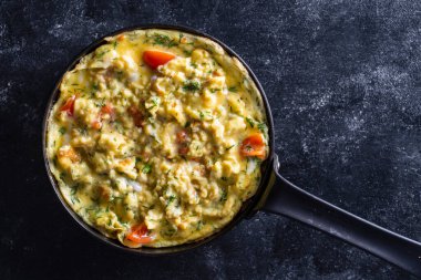 View of frying pan with fried eggs omelette on a black background , close up, top view, copy space