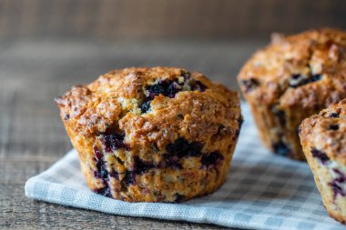 Delicious muffins with blueberries on a wooden table, close up. Sweet pastries on the board. Fresh cupcakes for breakfast