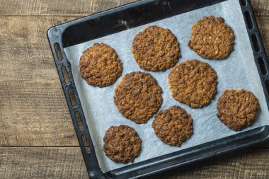 Delicious oatmeal cookies with walnuts on baking sheet, close up, top view