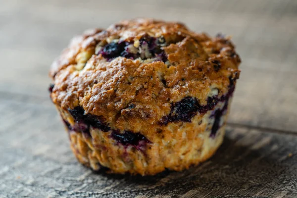 Delicious muffin with blueberries on a wooden table, close up. Sweet pastries on the board. Fresh cupcake for breakfast