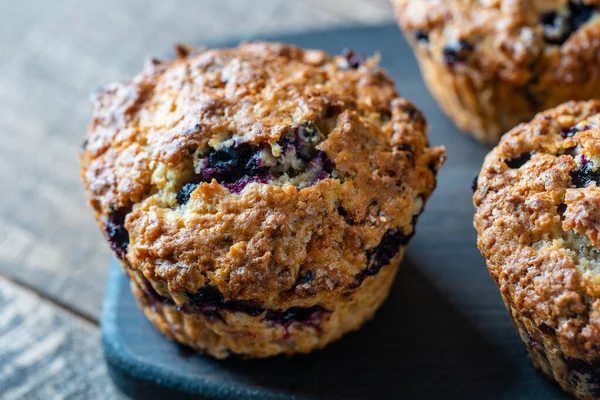 Delicious muffins with blueberries on a wooden table, close up. Sweet pastries on the board. Fresh cupcakes for breakfast