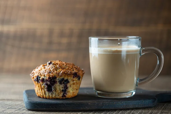 Köstliche Muffins Mit Blaubeeren Und Cappuccino Glas Auf Einem Holztisch — Stockfoto