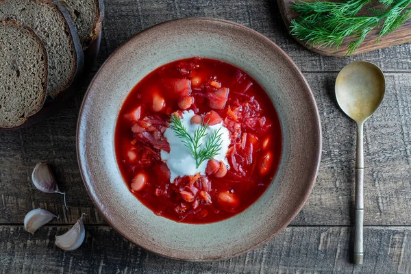 Ukrainian national dish red borsch in a ceramic plate on a wooden background. Beetroot soup is a national dish in Ukraine, close up, top view