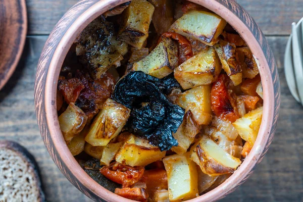 烤土豆 胡萝卜 西红柿和李子 放在木制桌子背景的黏土锅里 — 图库照片