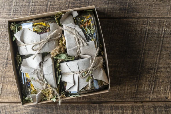 木製の背景にギフトボックスで乾燥した花やハーブティーと4つのガラス瓶 コピースペース トップビュー 茶の草本 — ストック写真