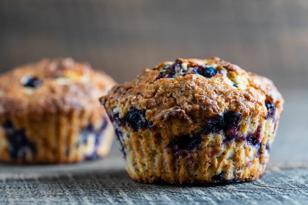 Delicious muffins with blueberries on a wooden table, close up. Sweet pastries on the board. Fresh cupcakes for breakfast