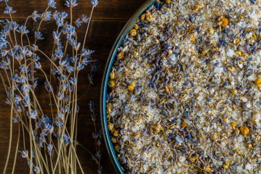 Ahşap arka planda kuru lavanta ve papatya çiçekli deniz Himalaya tuzu, yakın plan, üst manzara