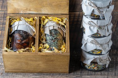 Glass jar with of flower tea and a glass jar with of pine cone jam in a wooden gift box on a table, close up. Beautiful present for family and friends